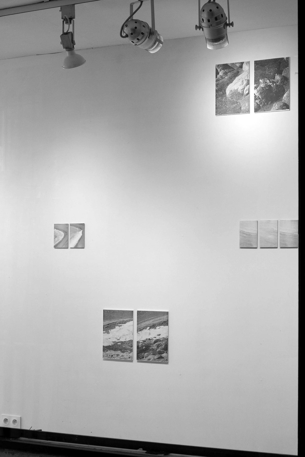 Vue de l’exposition à la Galerie Sono sous les projecteurs, les tirages accrochés en constellation sur le mur.
